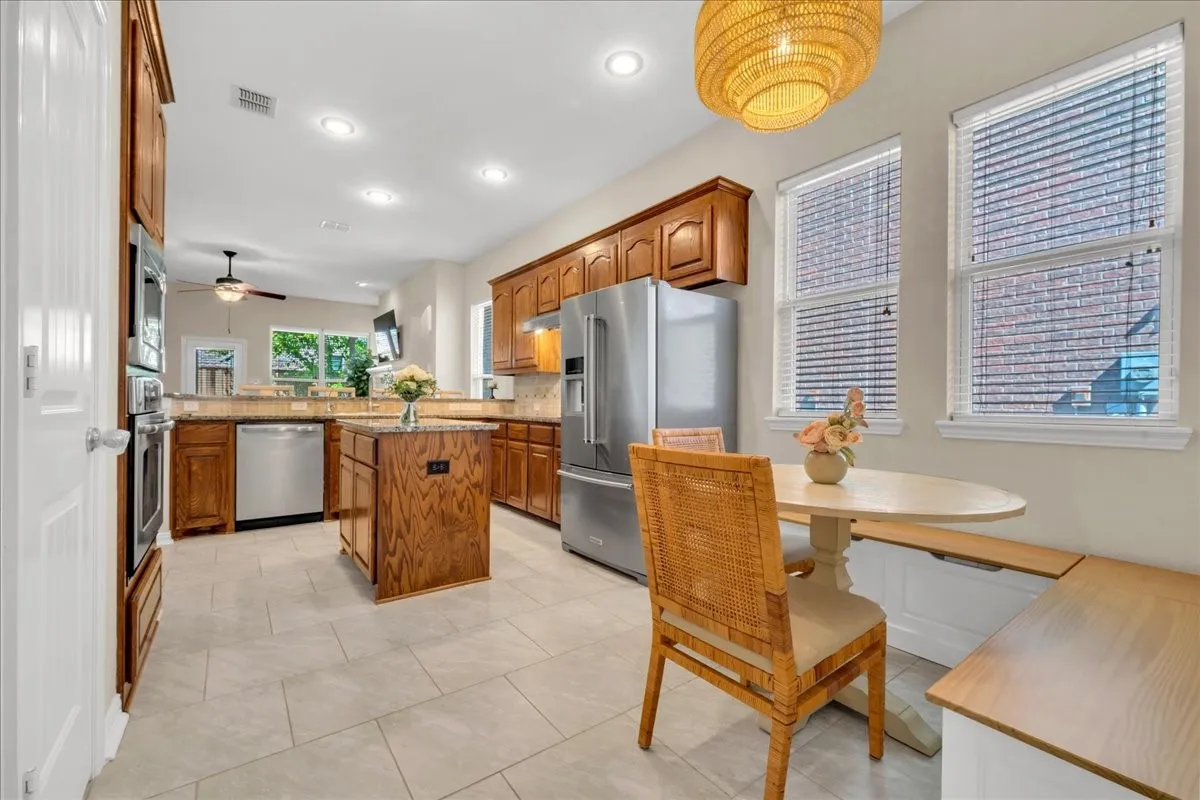 Kitchen featuring recessed lighting, a central island, wood cabinetry, stainless steel appliances, and tile flooring