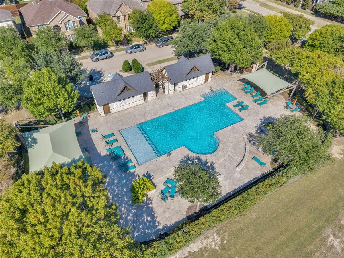 Community swimming pool with an integrated spa, surrounded by a concrete deck, and two shade structures