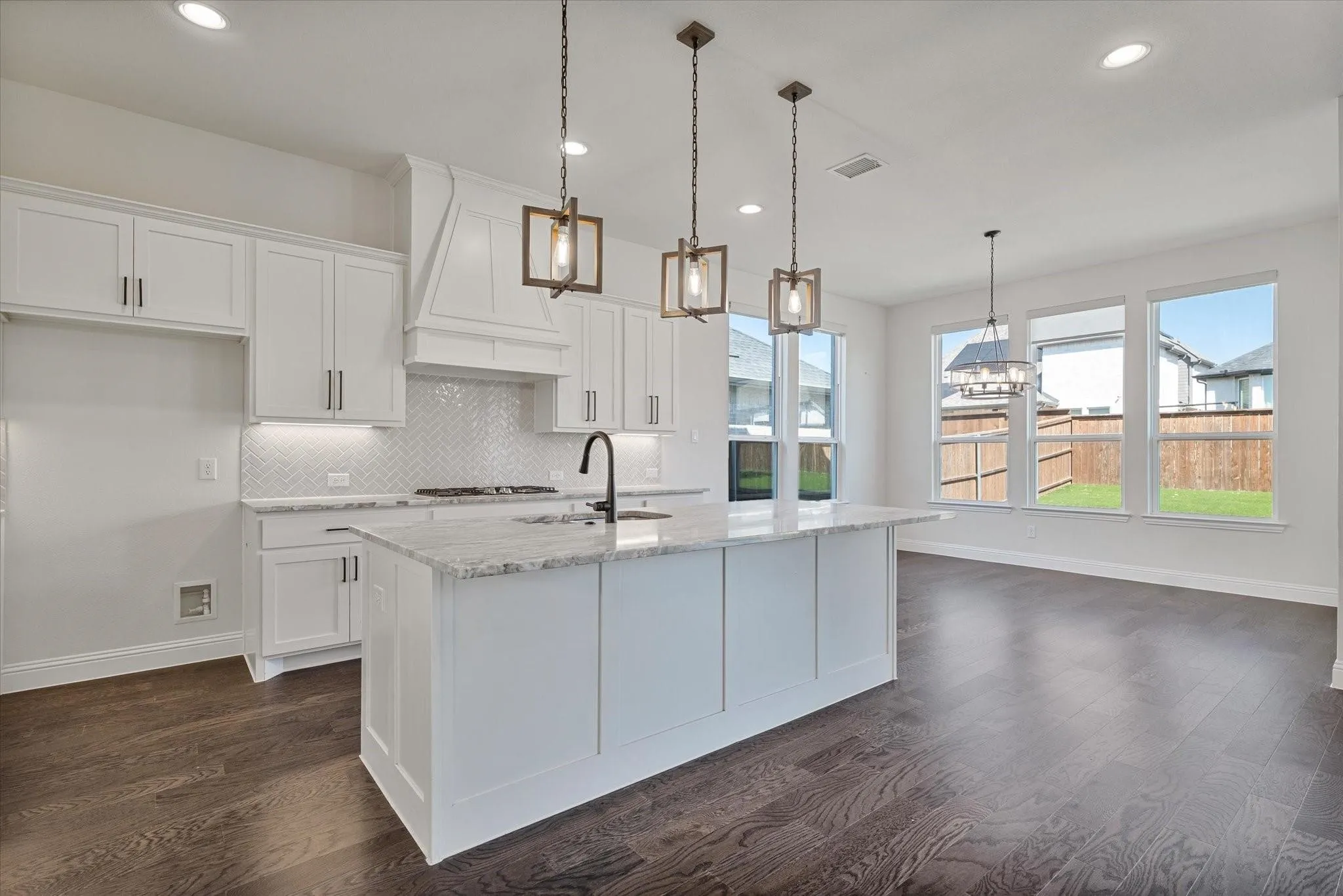 Kitchen featuring white cabinetry, quartz countertops, herringbone pattern tile backsplash, a center island with a matte black faucet, and wood-finish flooring