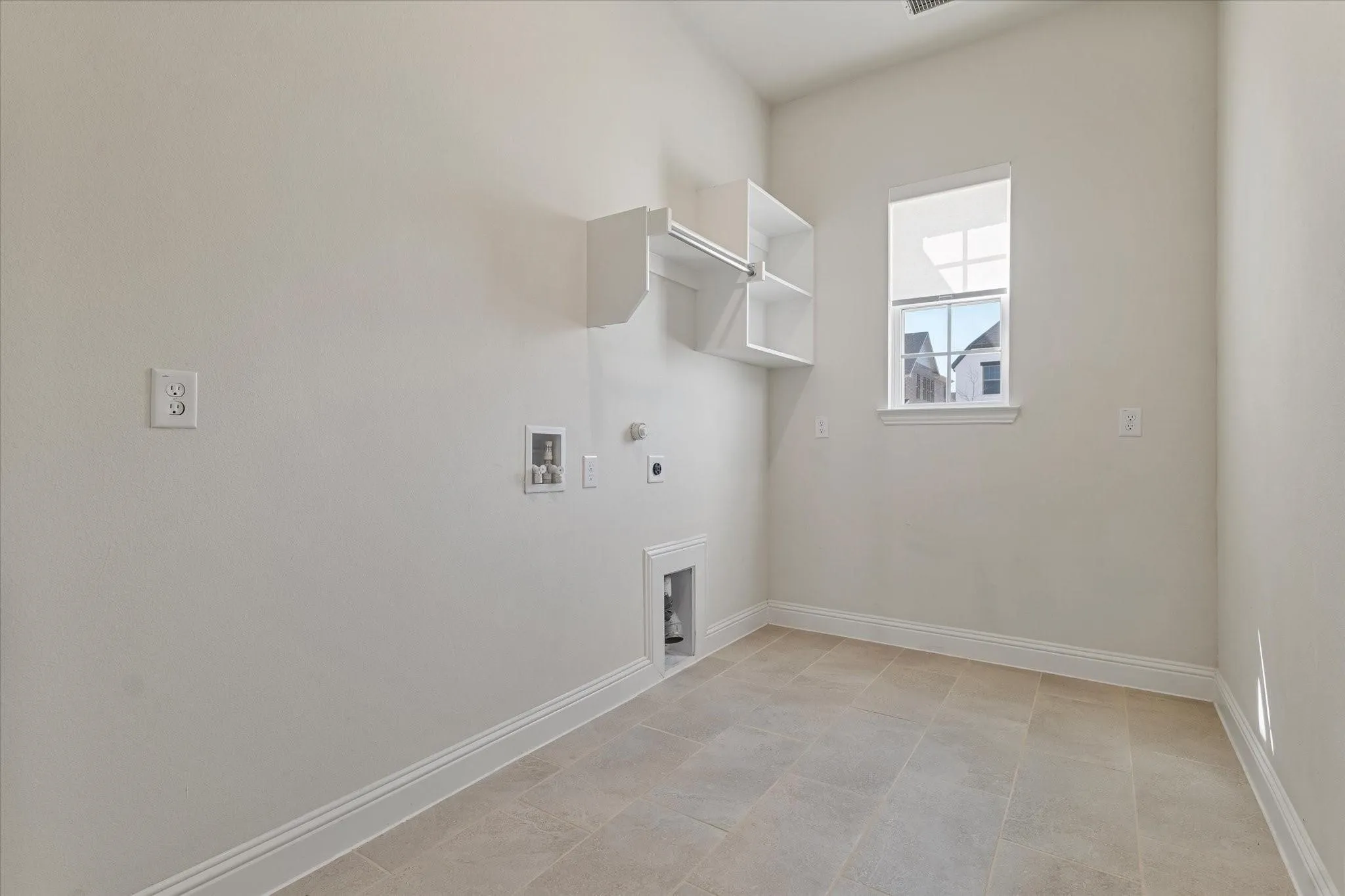 Utility space featuring tile flooring, a single window with muntins, and built-in wall shelving with a hanging rod