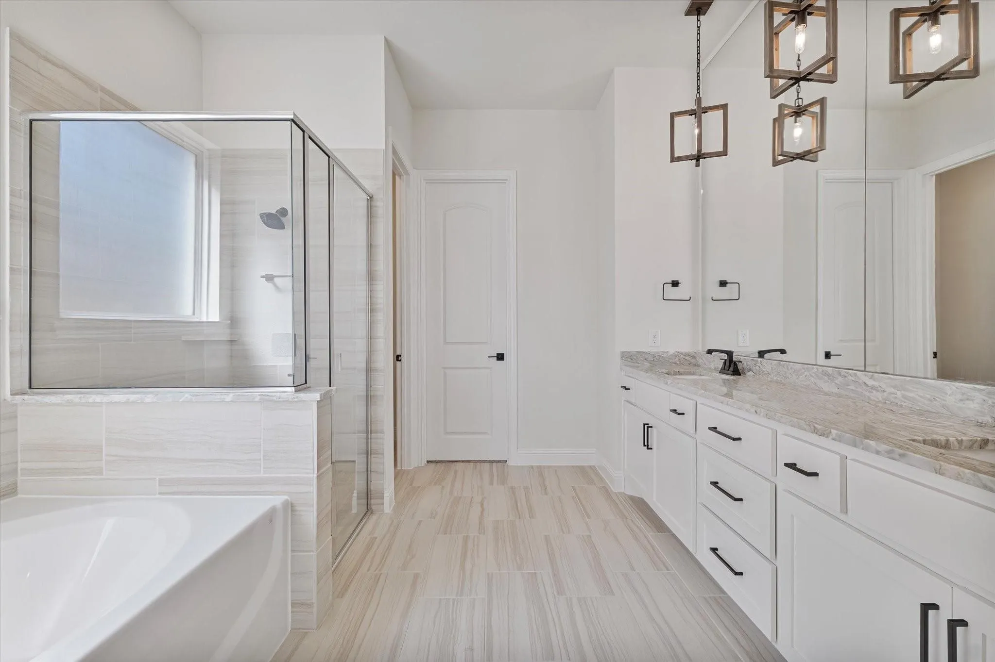 Dual-sink vanity with stone-finish countertops and matte black hardware, tiled walk-in shower with glass enclosure, freestanding soaking tub, and geometric pendant lighting