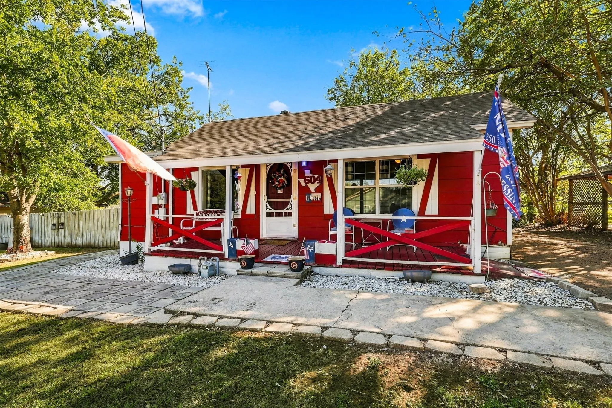 Cottage-style exterior featuring a covered front porch with cross-buck railing, horizontal siding, and a stone-paver walkway