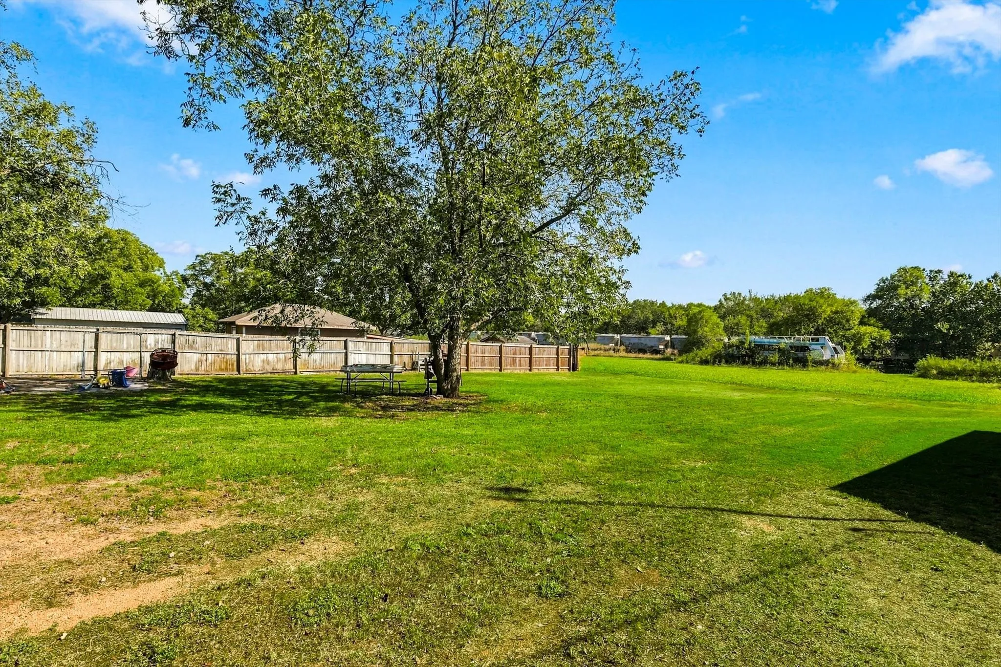 Expansive lawn featuring mature trees and a perimeter wood-slat fence