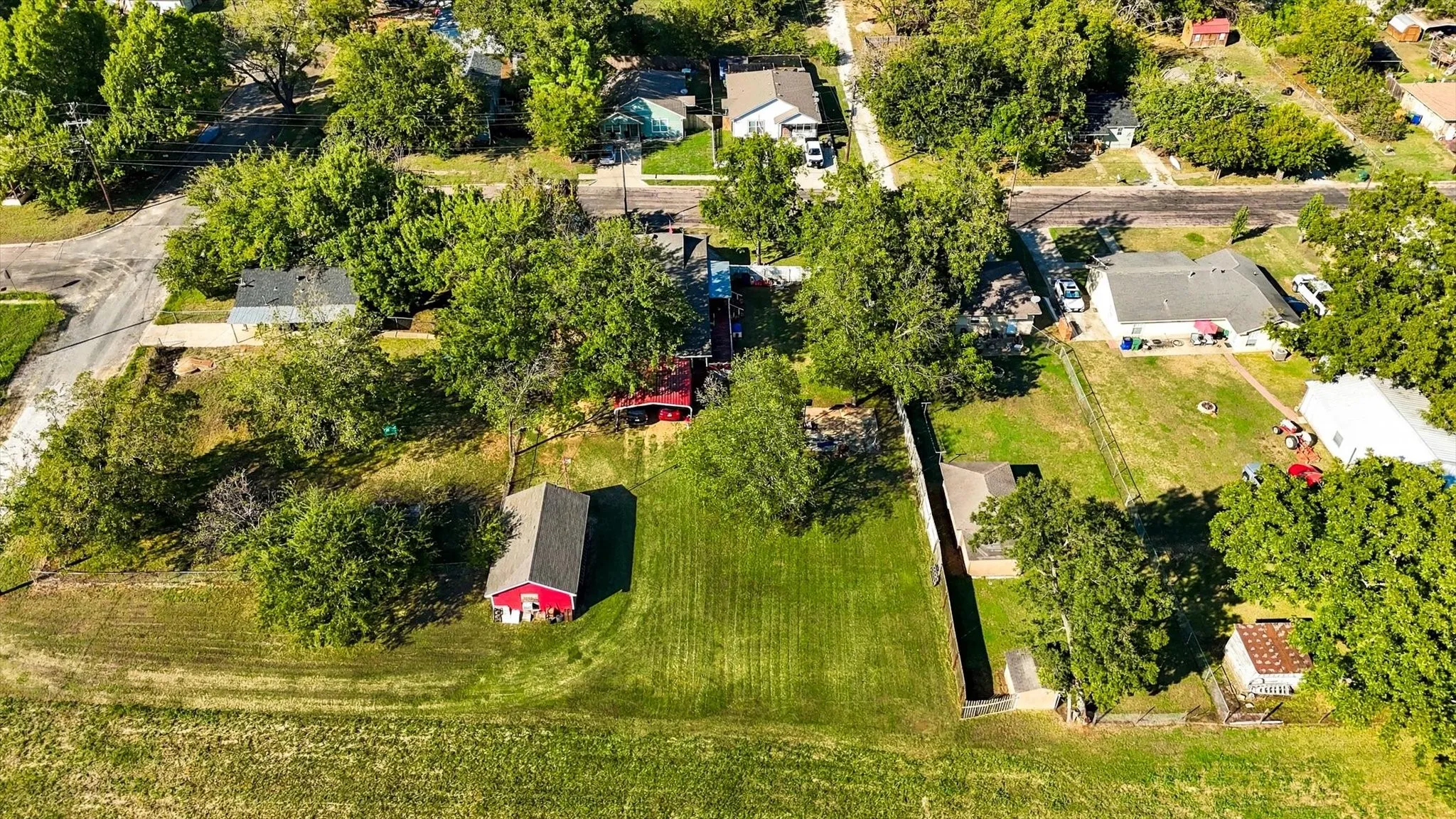 Expansive lot featuring mature trees, manicured lawn, and a detached structure with a pitched roof