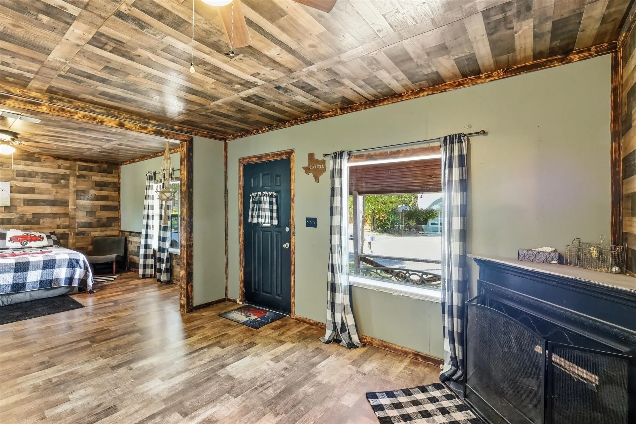 Wood-finish flooring, reclaimed-style plank ceiling, dark-tone fireplace surround, and custom wooden trim detailing