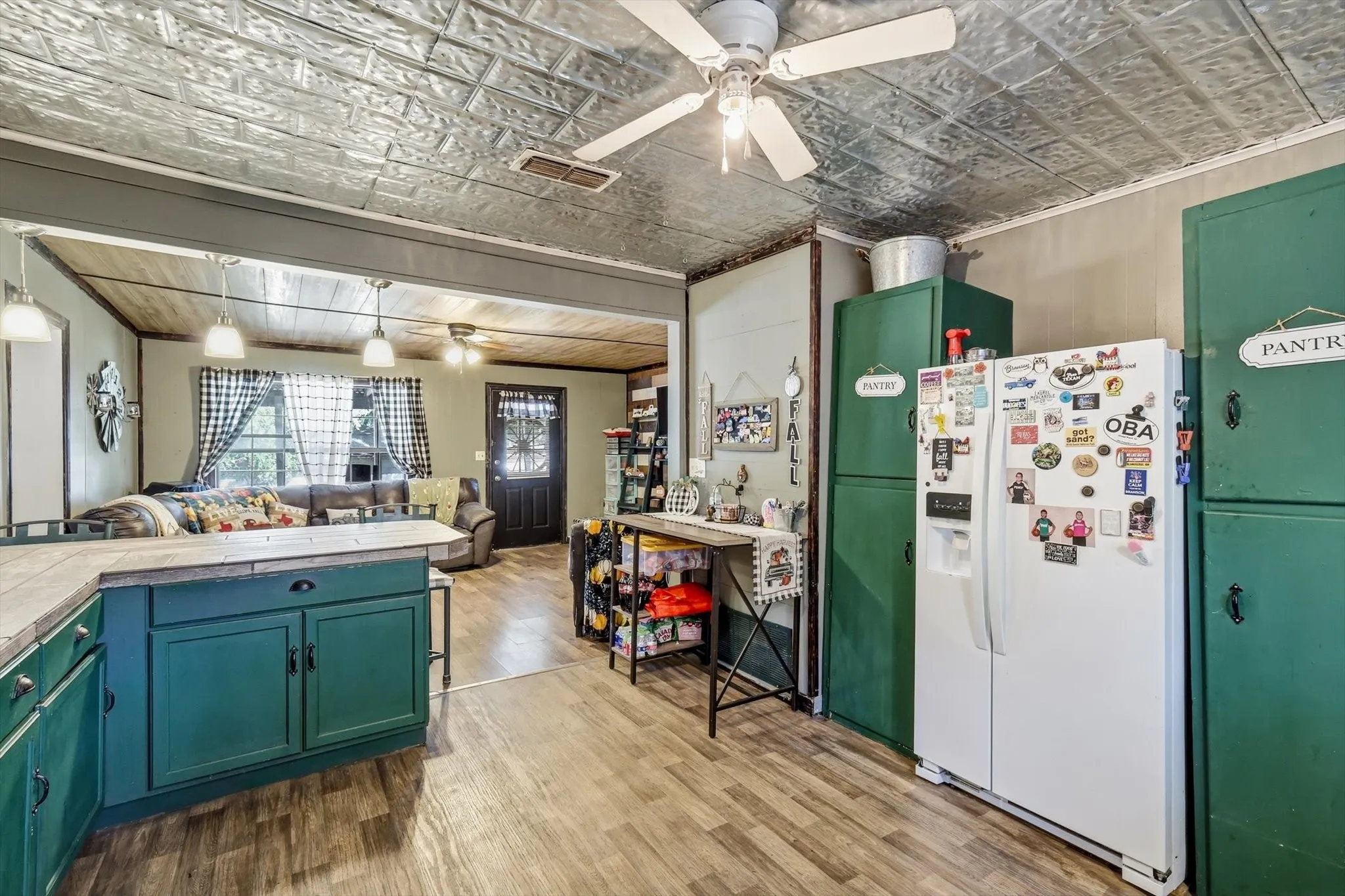 Kitchen featuring a metallic-finish decorative ceiling, wood-finish flooring, green painted cabinetry, and an integrated pantry