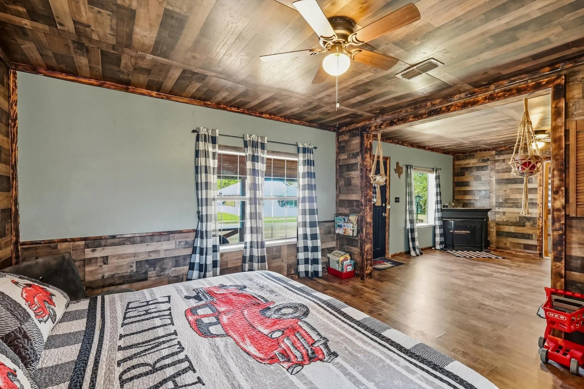 Wood-plank ceiling and wall accents, wood-finish flooring, and a ceiling fan with integrated lighting