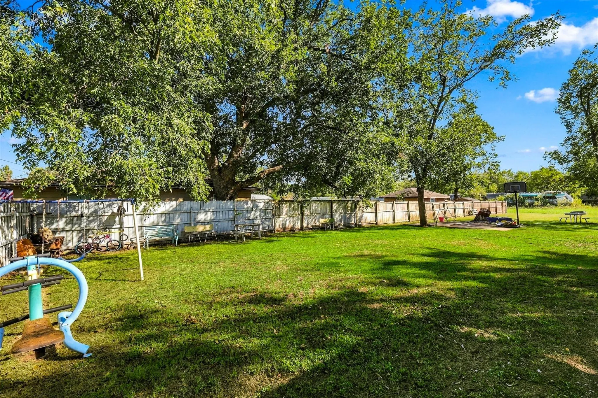 Expansive backyard featuring a large grass lawn, mature trees, and a full-perimeter privacy fence