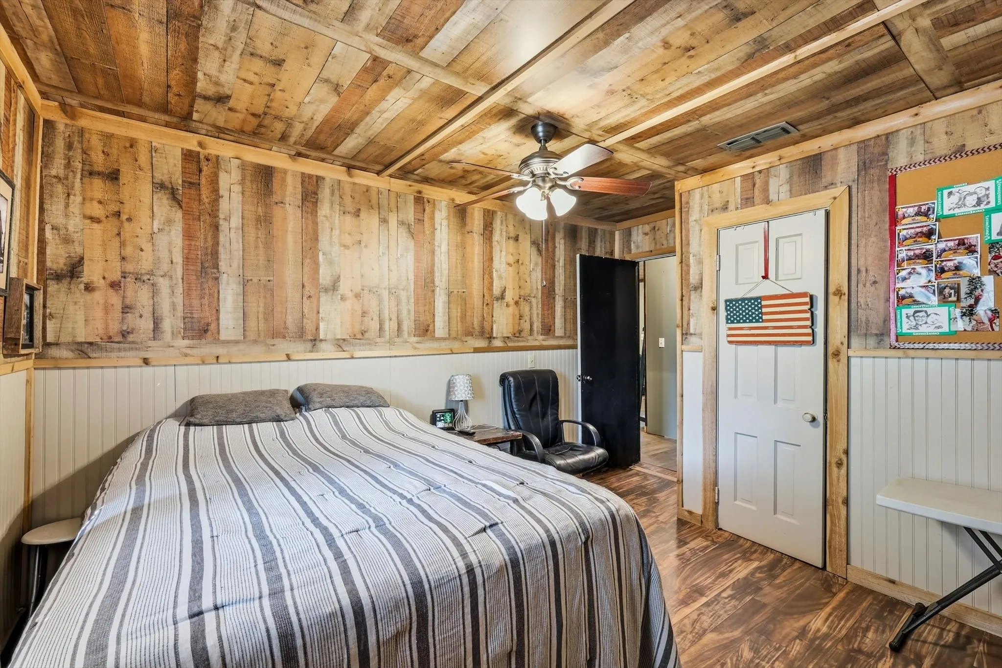 Reclaimed wood-finish wall and ceiling paneling, wood-finish flooring, white beadboard wainscoting, and a multi-blade ceiling fan with integrated lighting