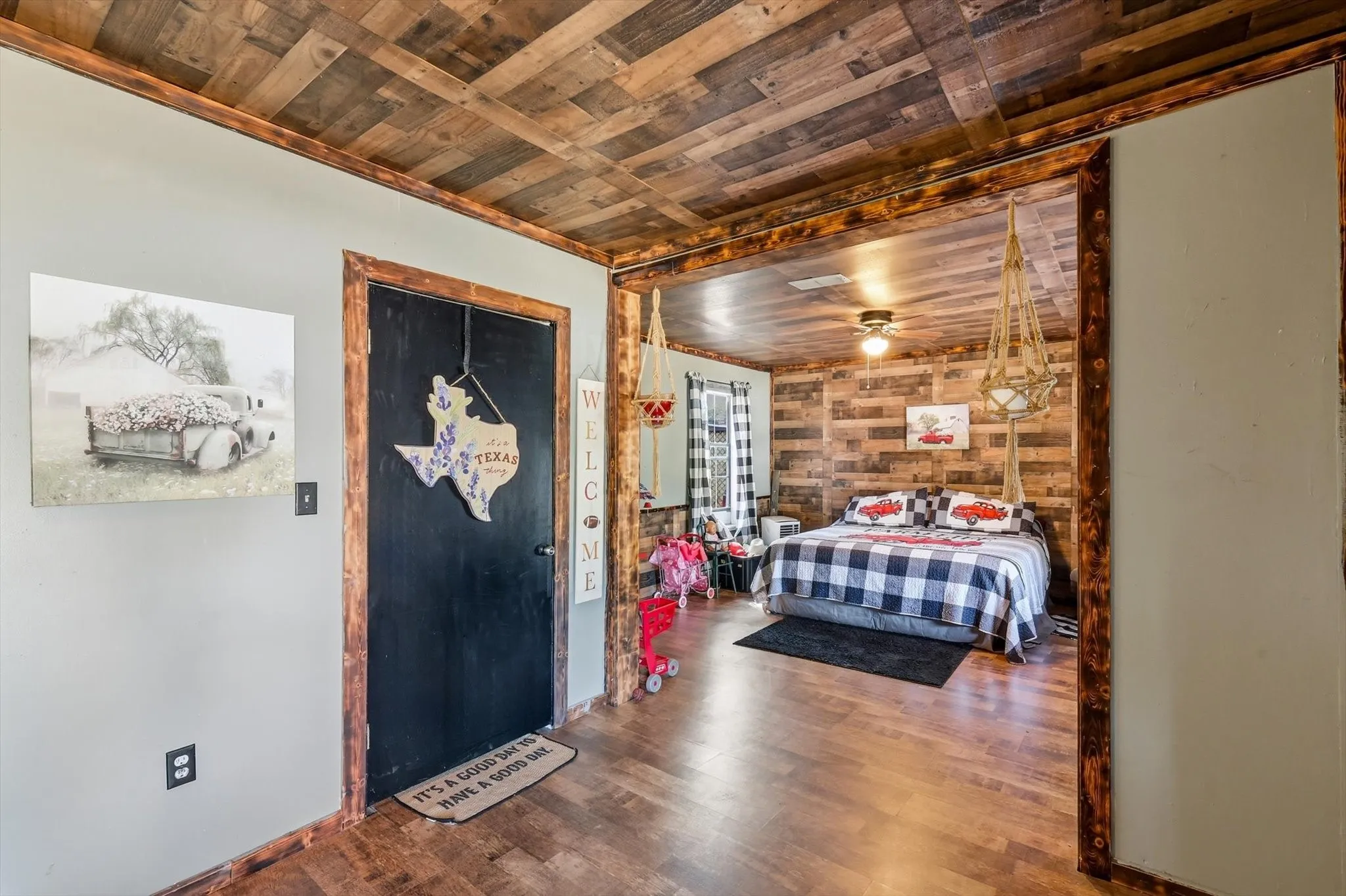 Interior space featuring wood-plank ceiling treatment, rustic wood trim, wood-finish flooring, and a solid black door