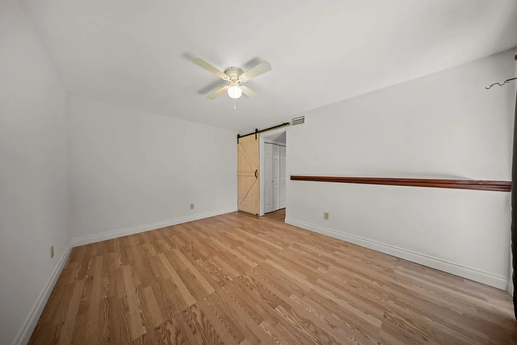 Room interior featuring wood-finish flooring, a light-toned sliding barn door, and a wooden chair rail accent