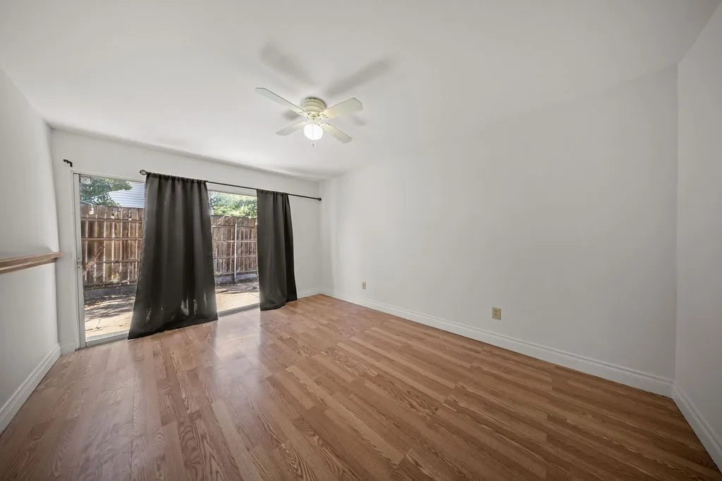 Wood-finish flooring, sliding glass door, and a ceiling-mounted light fixture with fan