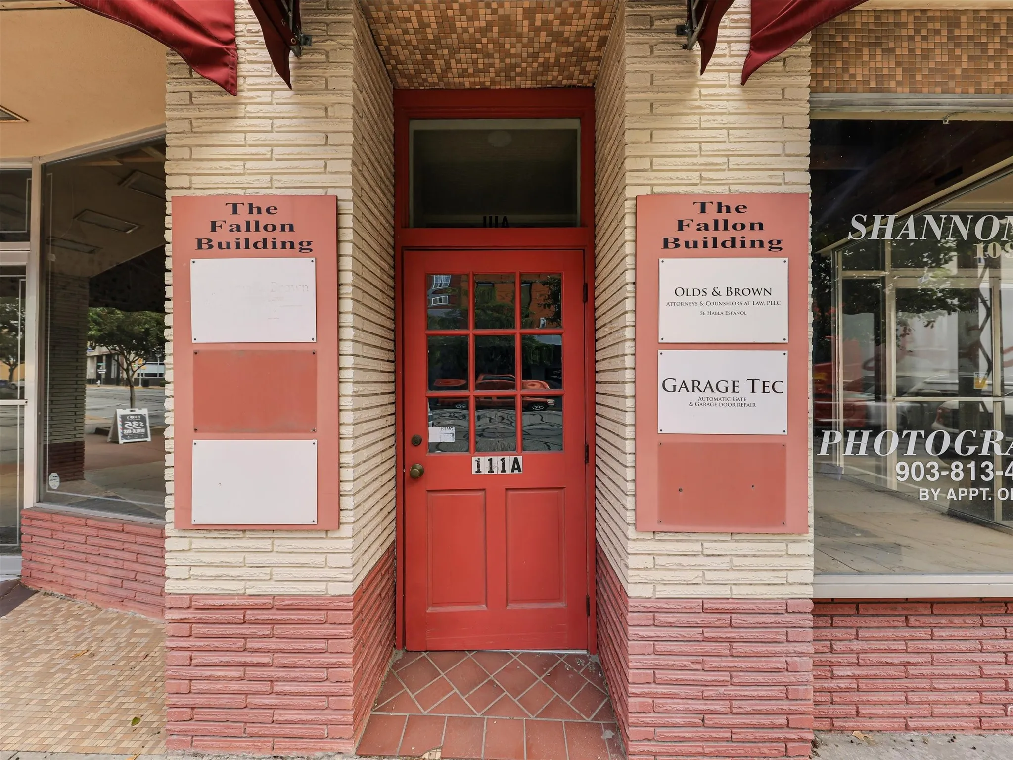 Entryway featuring cream and terra-cotta brick masonry, a nine-pane glass and wood door, and integrated building signage