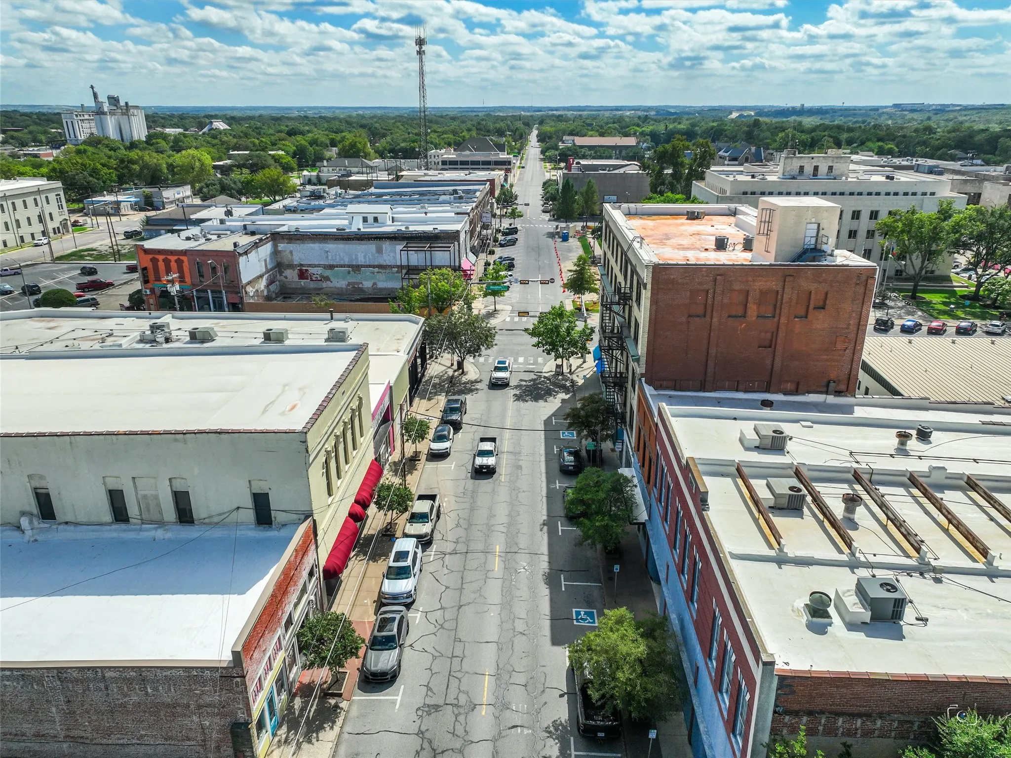 Aerial perspective of a central urban corridor featuring brick masonry structures, flat rooflines, and street-level parking