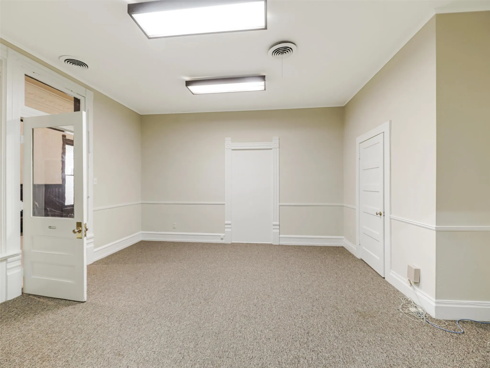 Interior room featuring neutral wall paint, white chair rail molding, a classic five-panel interior door, and a glass-paneled entry door with traditional hardware