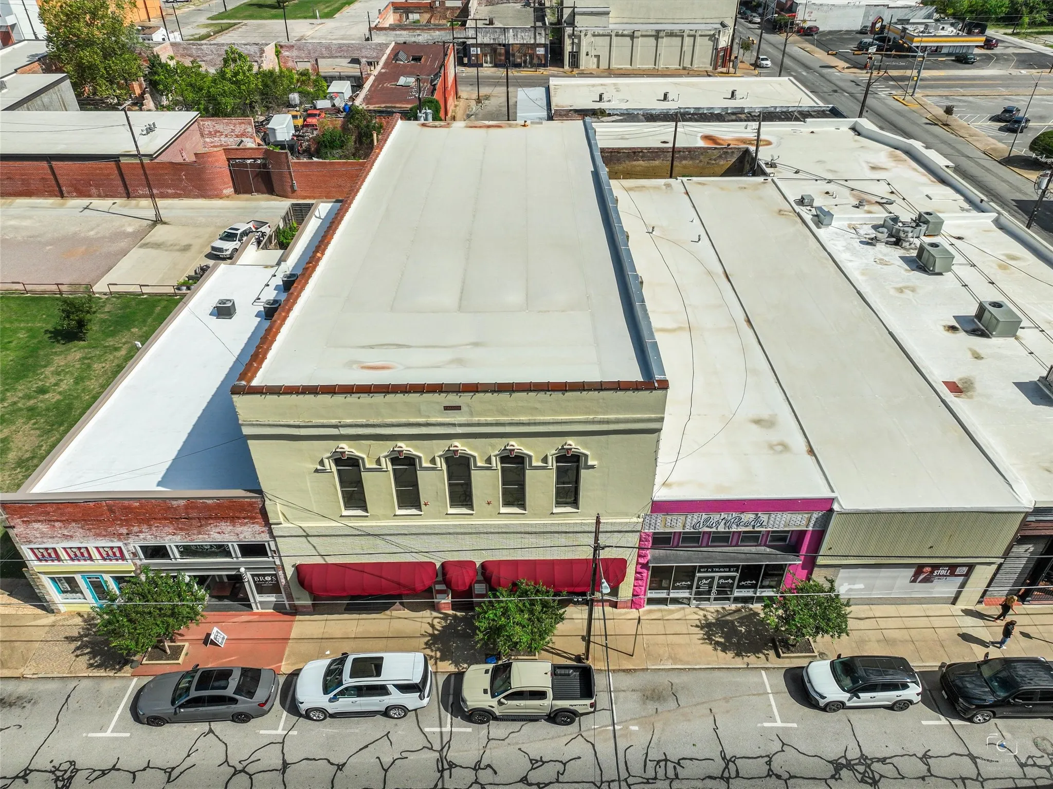 Commercial building exterior featuring a light-colored masonry facade, arched window detailing, and retractable fabric awnings
