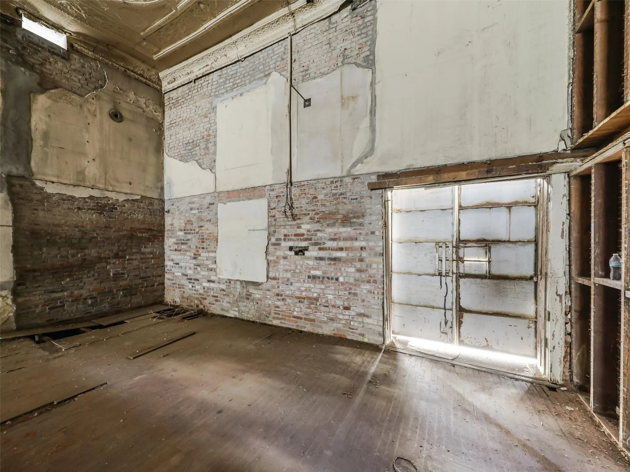 Interior space featuring exposed brick masonry, high ceilings with decorative plaster molding, and industrial metal double doors