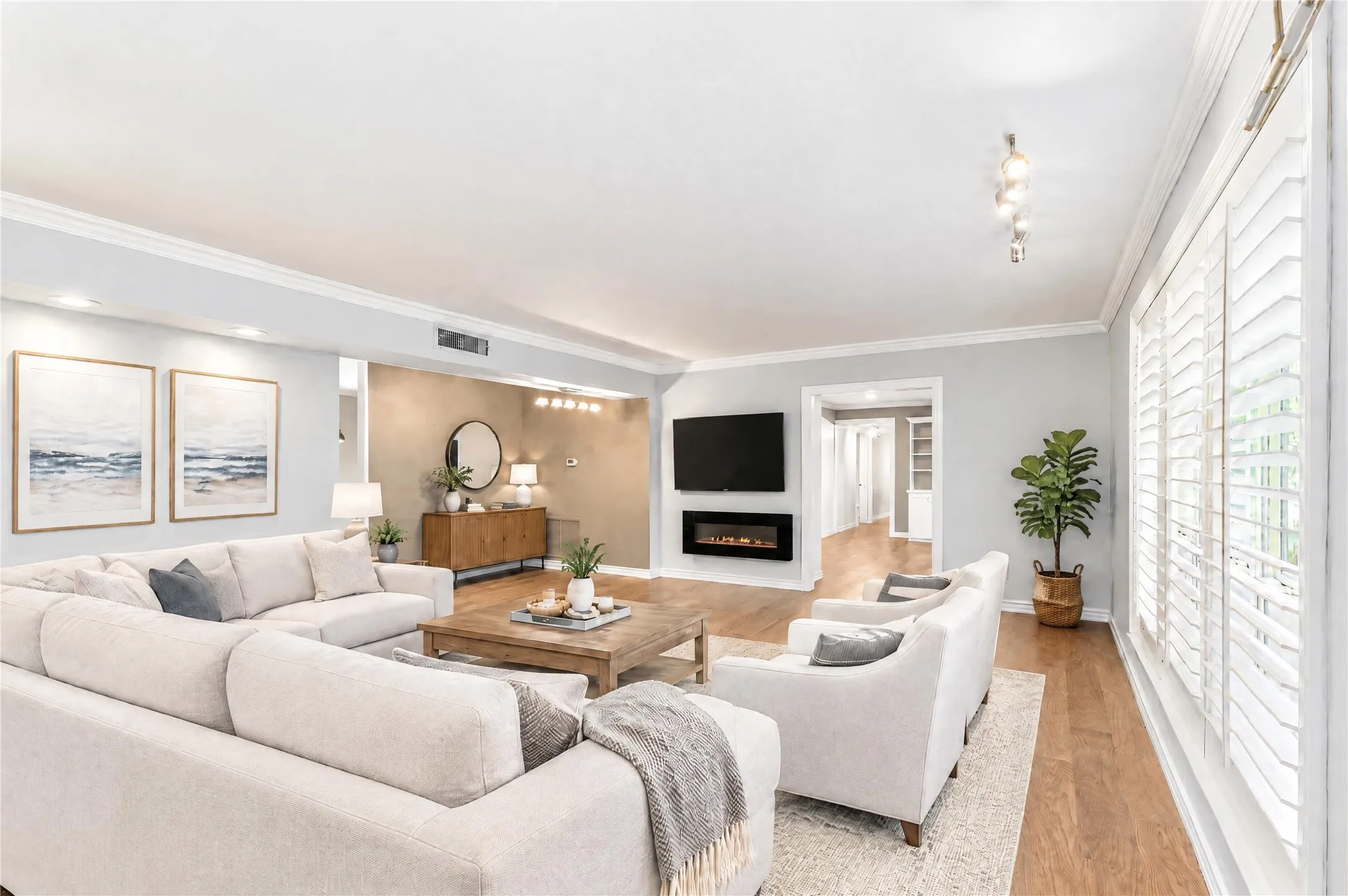 Living area featuring wood-finish flooring, crown molding, plantation shutters, and a wall-mounted electric fireplace