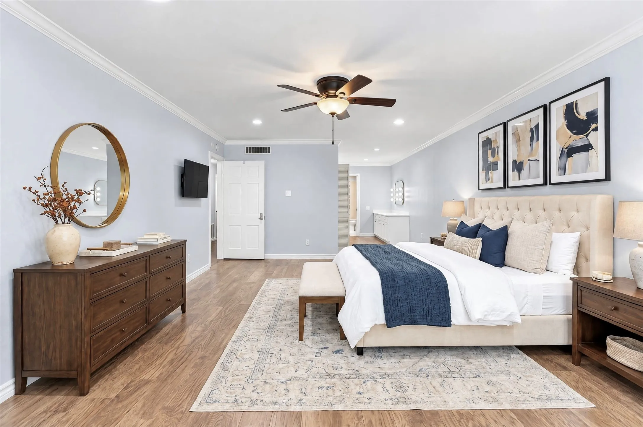 Spacious room featuring wood-finish flooring, crown molding, a central ceiling fan with integrated lighting, and recessed ceiling lights