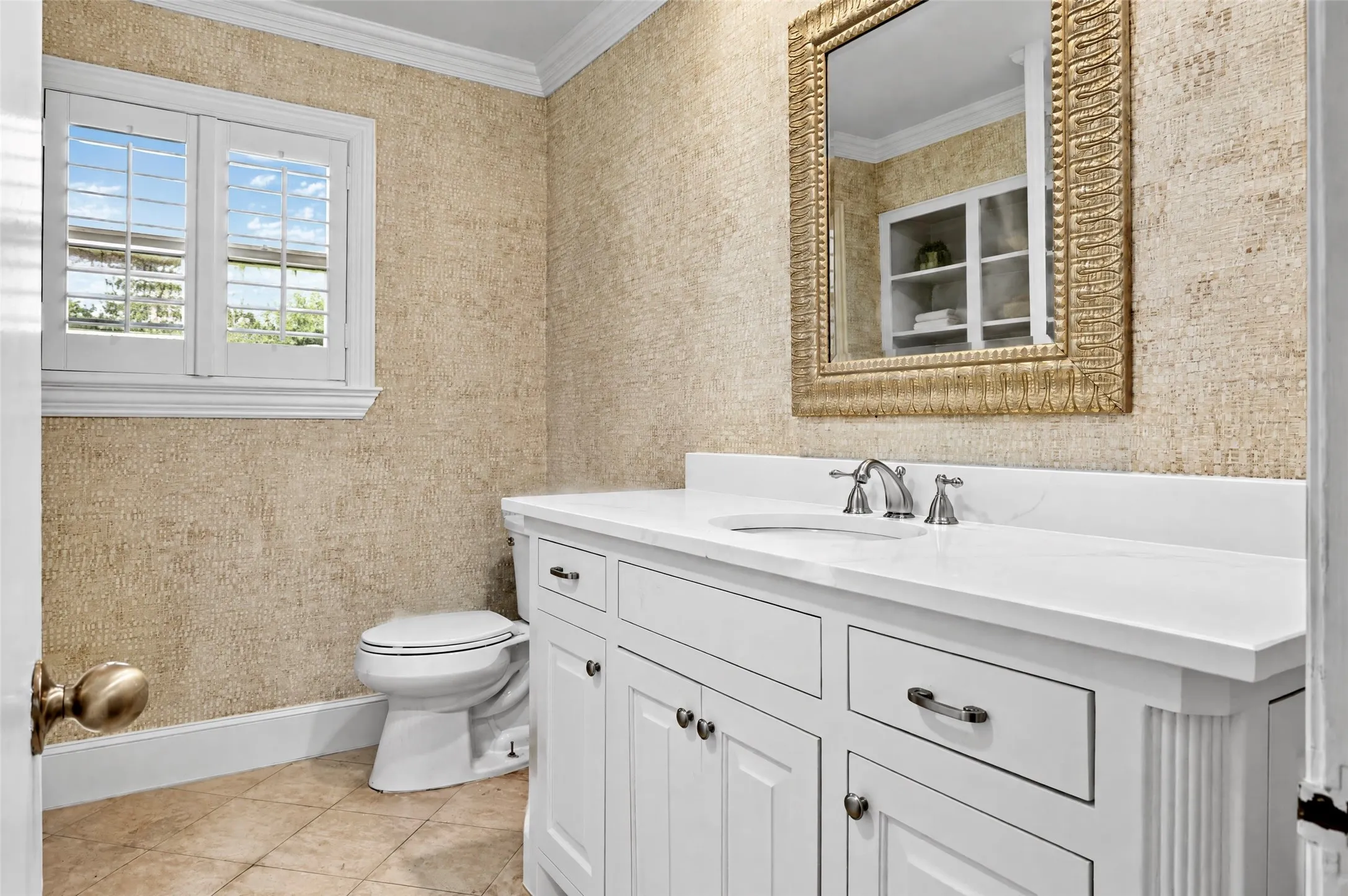 White vanity with an integrated sink and countertop, textured wall covering, plantation shutters, and crown molding