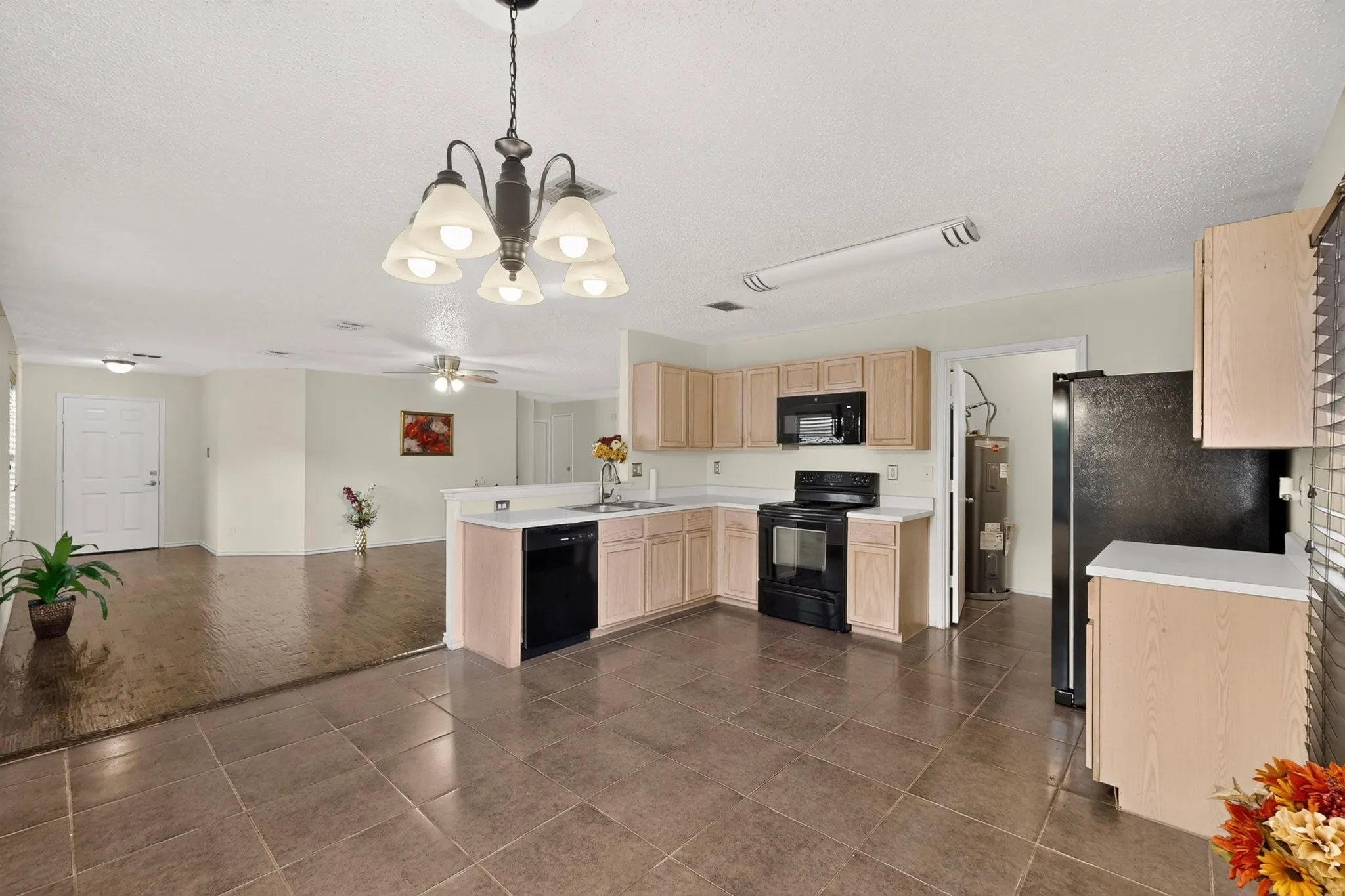 Kitchen featuring light-finish cabinetry, black appliances, tile flooring, and a multi-arm chandelier