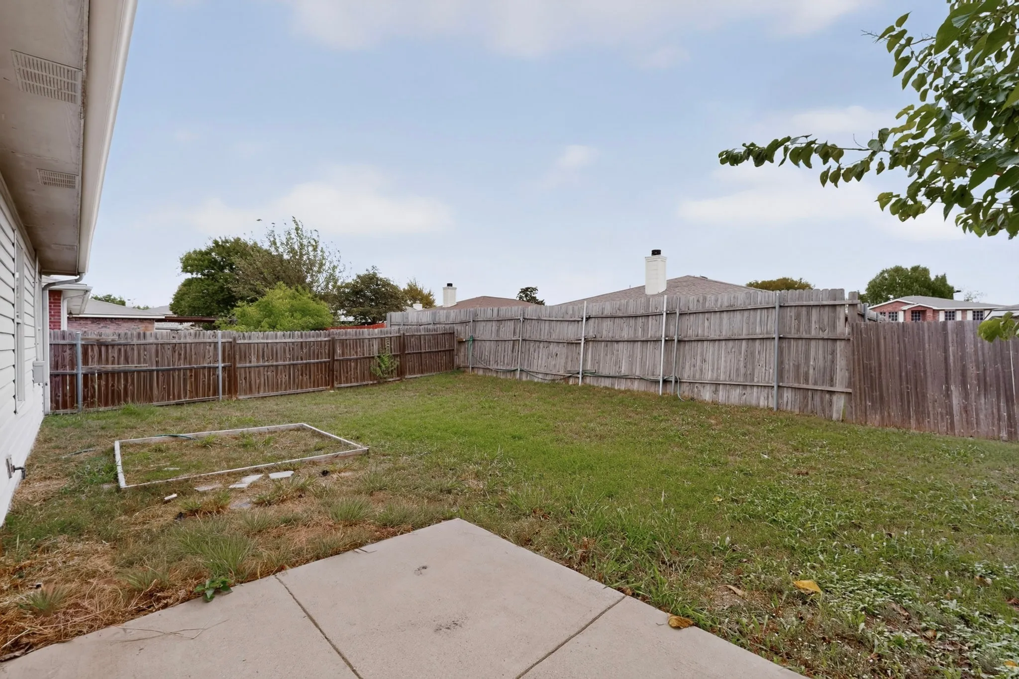 Backyard featuring a concrete patio, wood fence, and grass lawn