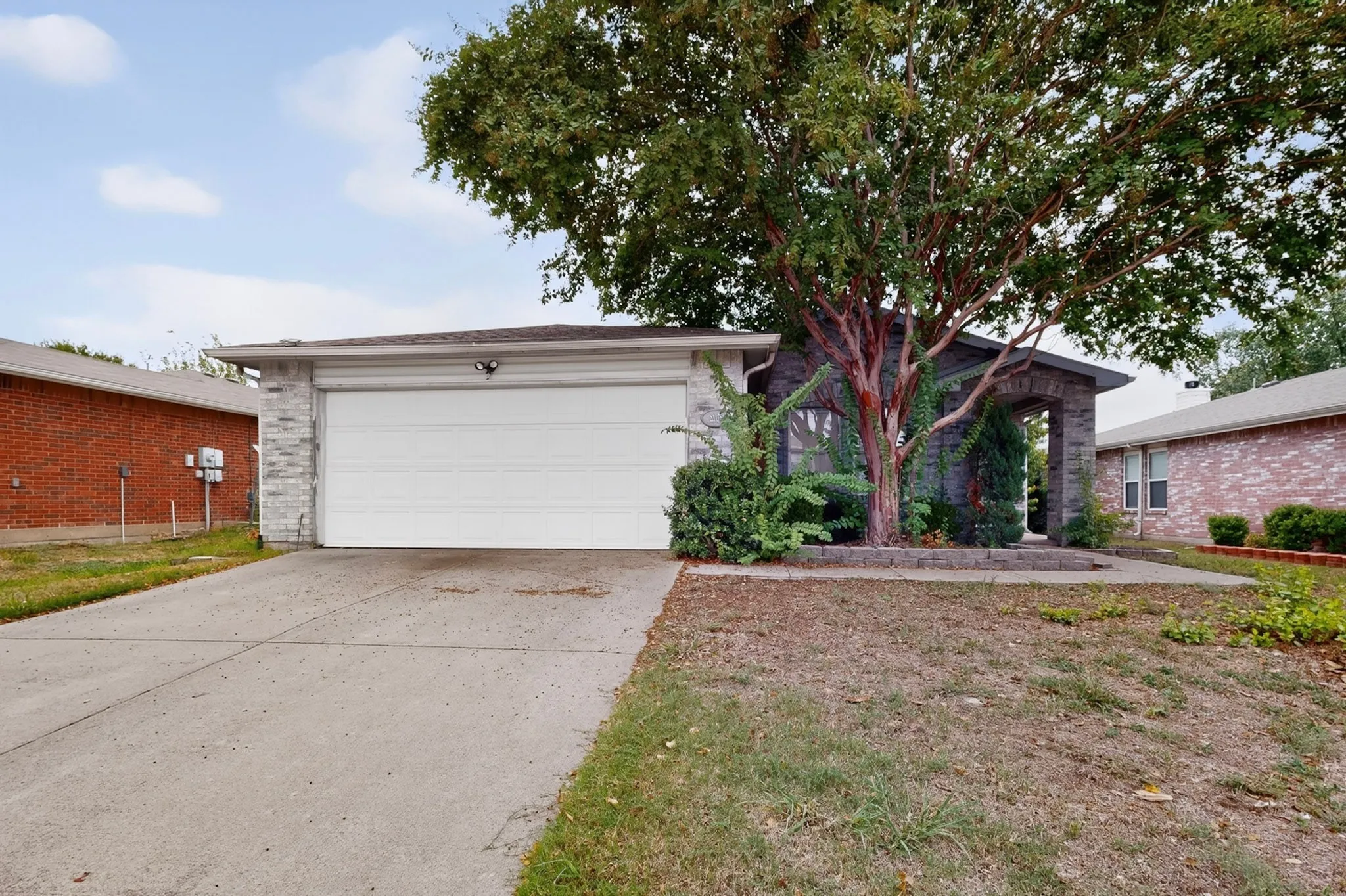 Exterior facade featuring grey stone veneer, a two-car attached garage, and a concrete driveway