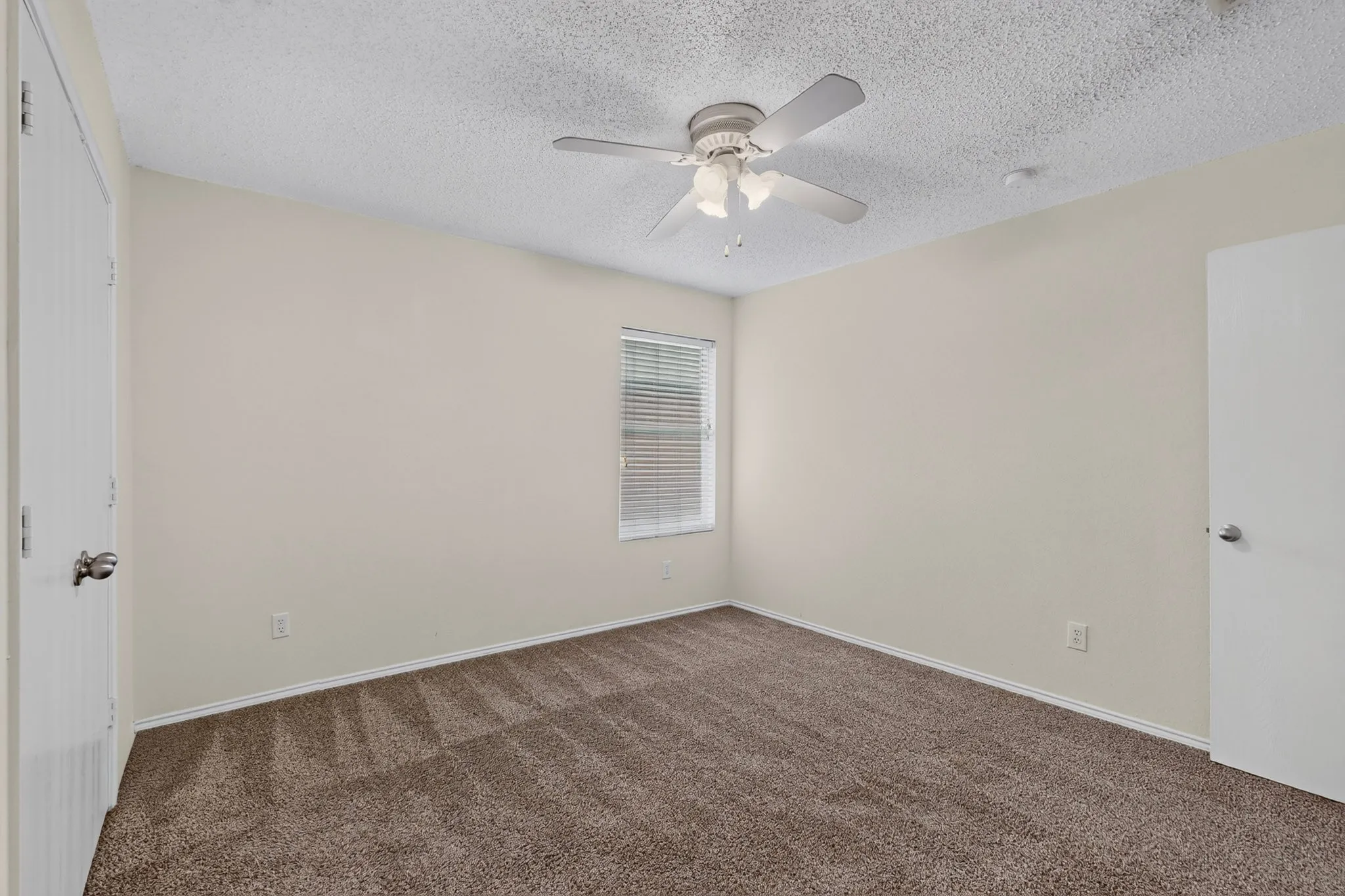 Interior space featuring wall-to-wall carpeting, neutral-toned walls, a central ceiling fan with integrated lighting, and a window with horizontal blinds