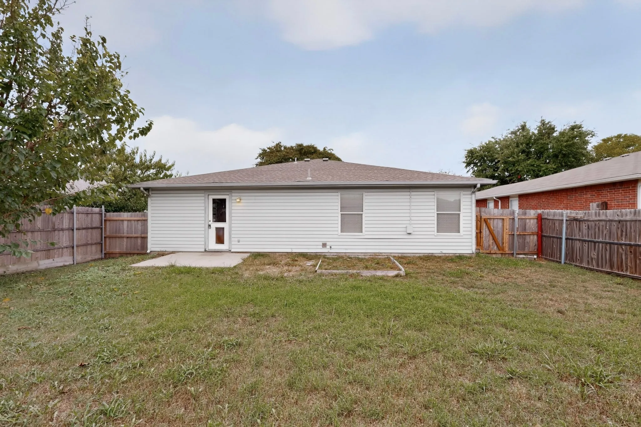 Rear exterior featuring horizontal vinyl siding, a concrete patio, and a fenced-in yard