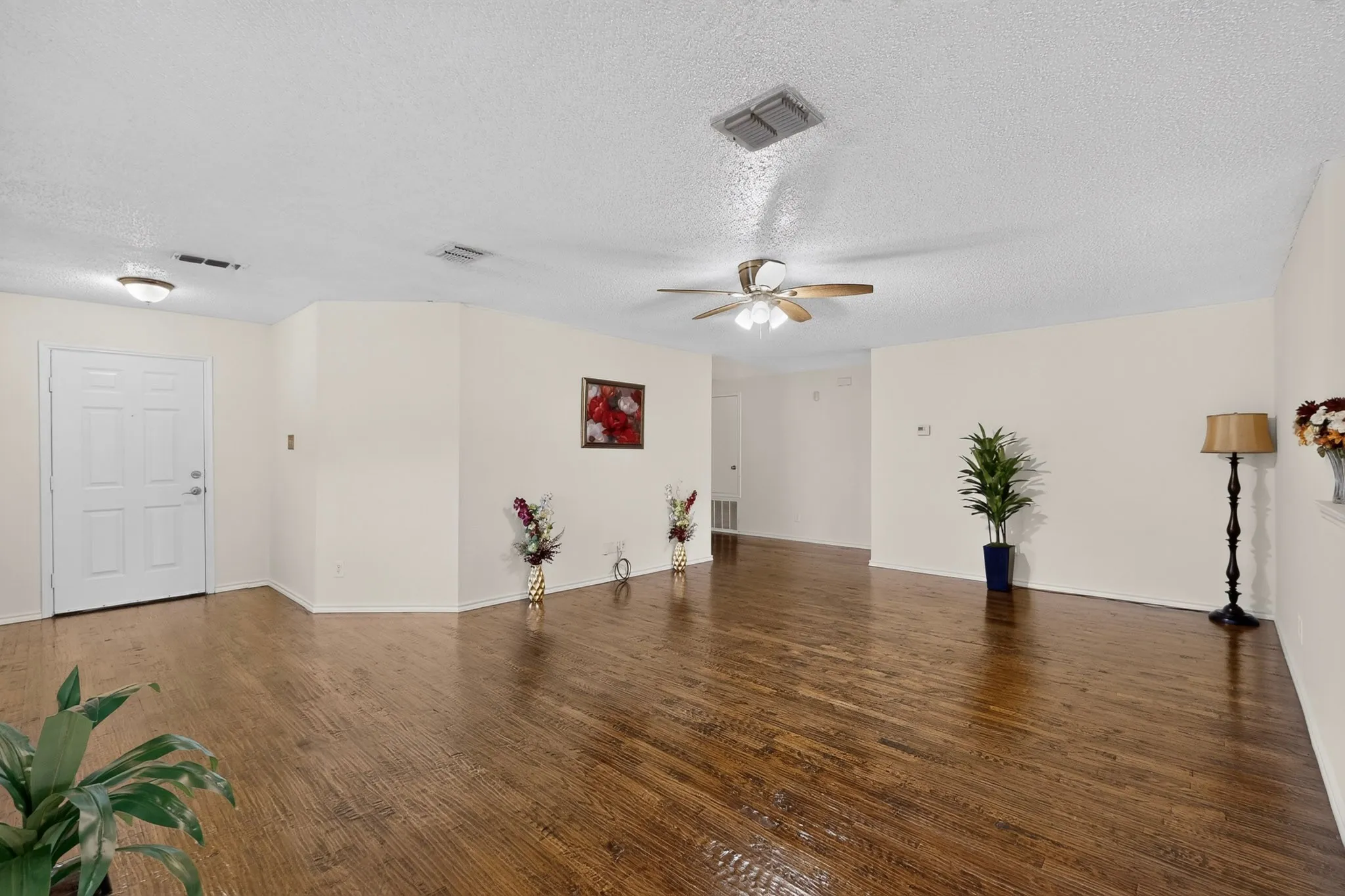 Open-concept room featuring wood-finish flooring, a multi-paneled entry door, and a ceiling-mounted fan with light fixture