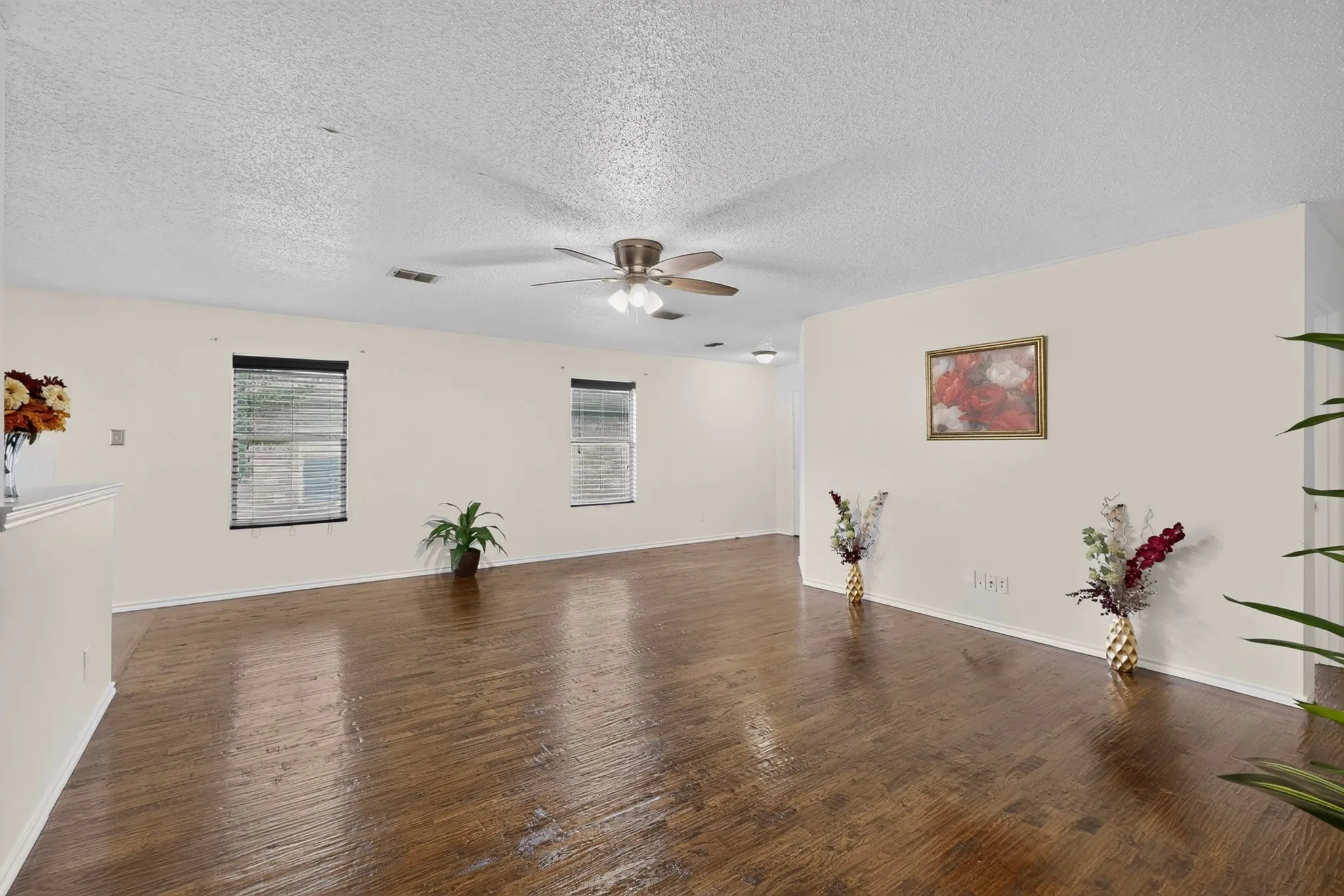 Living area featuring wood-finish flooring, neutral wall paint, and a ceiling-mounted fan with integrated lighting