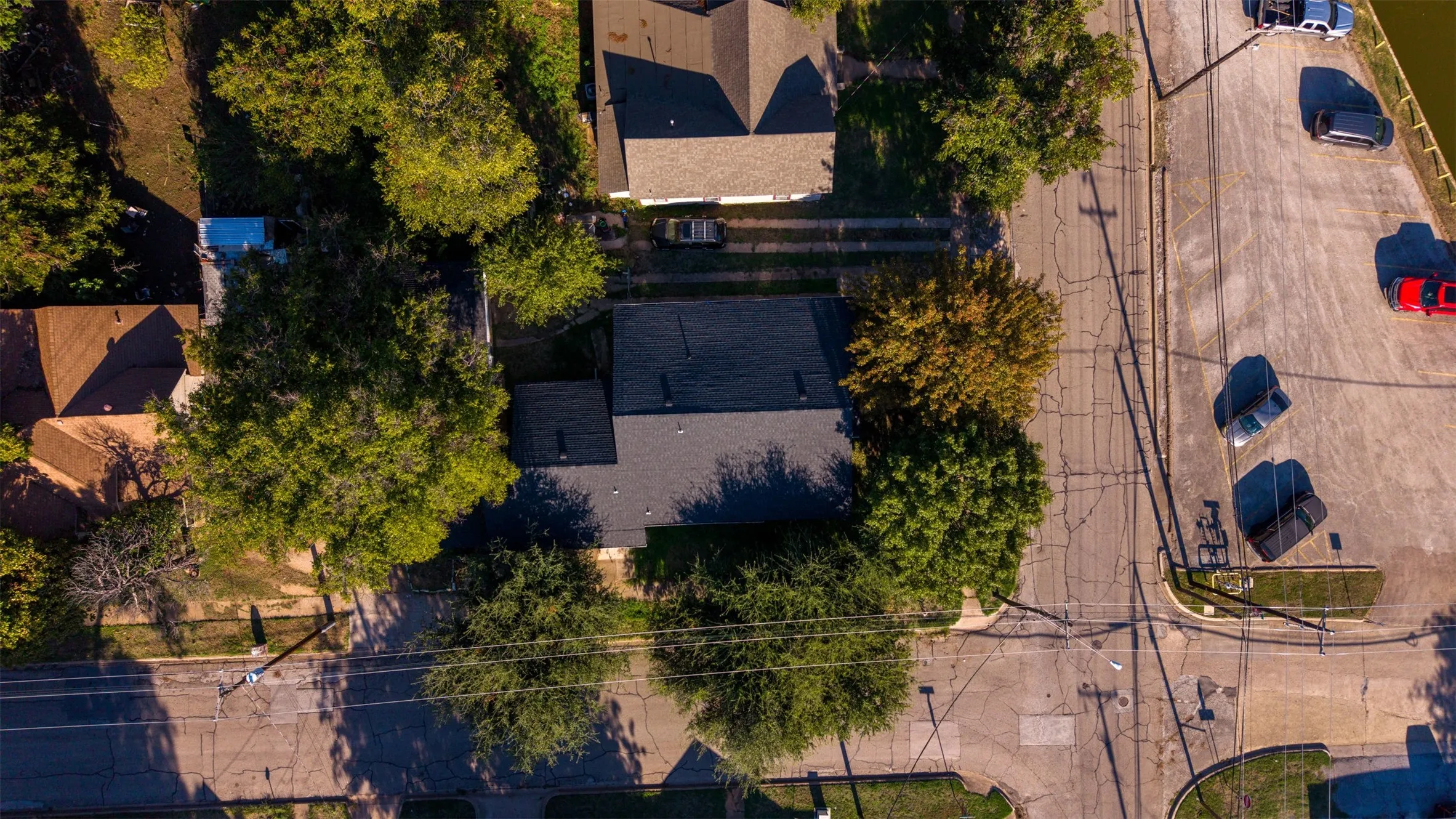 Aerial perspective featuring a shingled roof, corner lot placement, and mature tree canopy