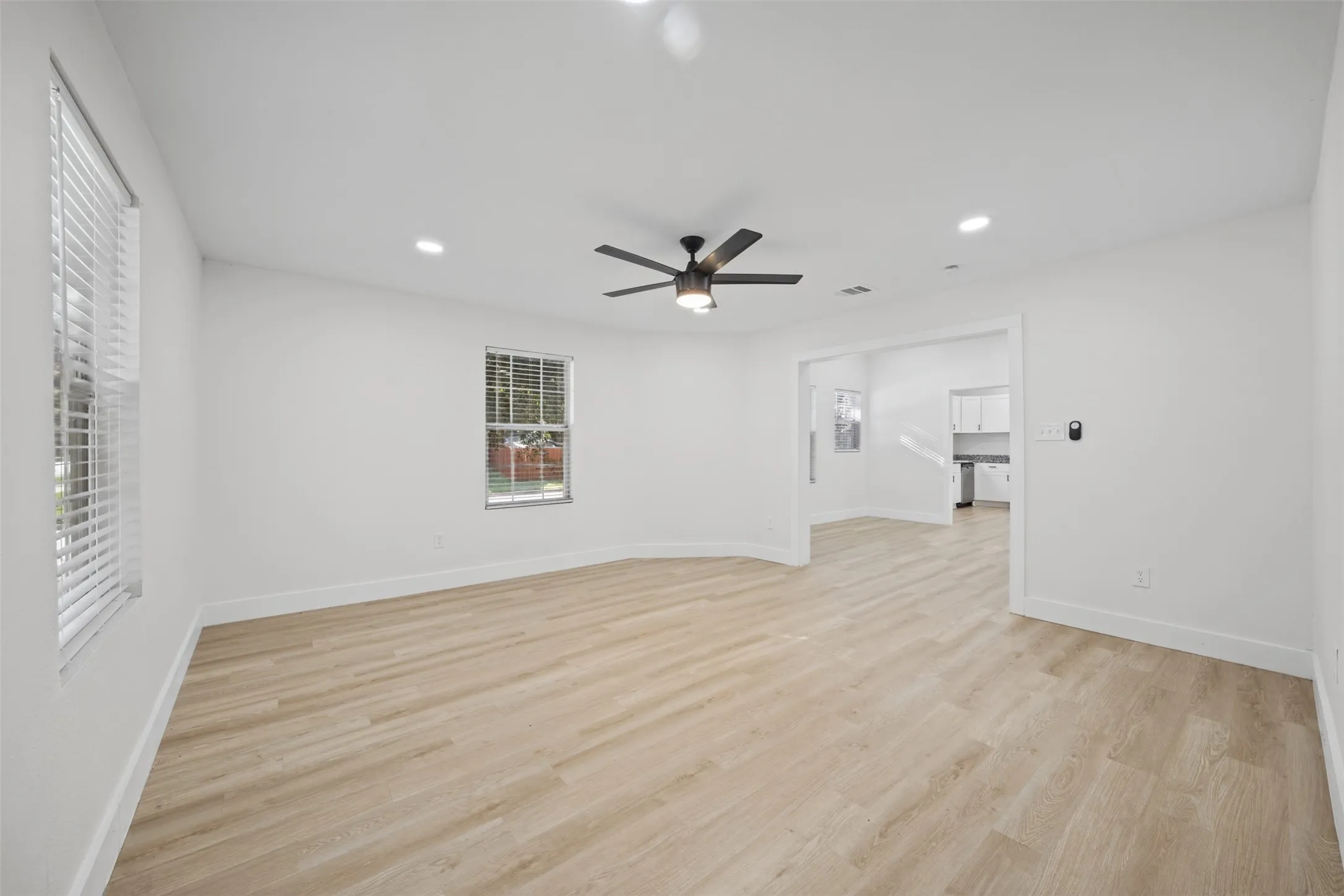 Interior space featuring wood-finish flooring, recessed lighting, a ceiling fan with integrated lighting, and horizontal window blinds