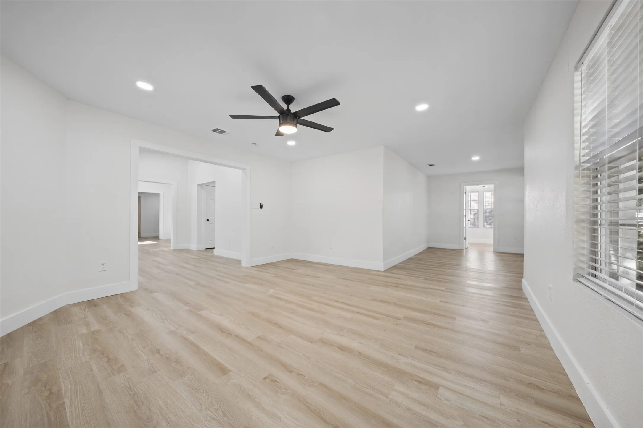 Interior space featuring wood-finish flooring, recessed lighting, matte black ceiling fan, and window blinds