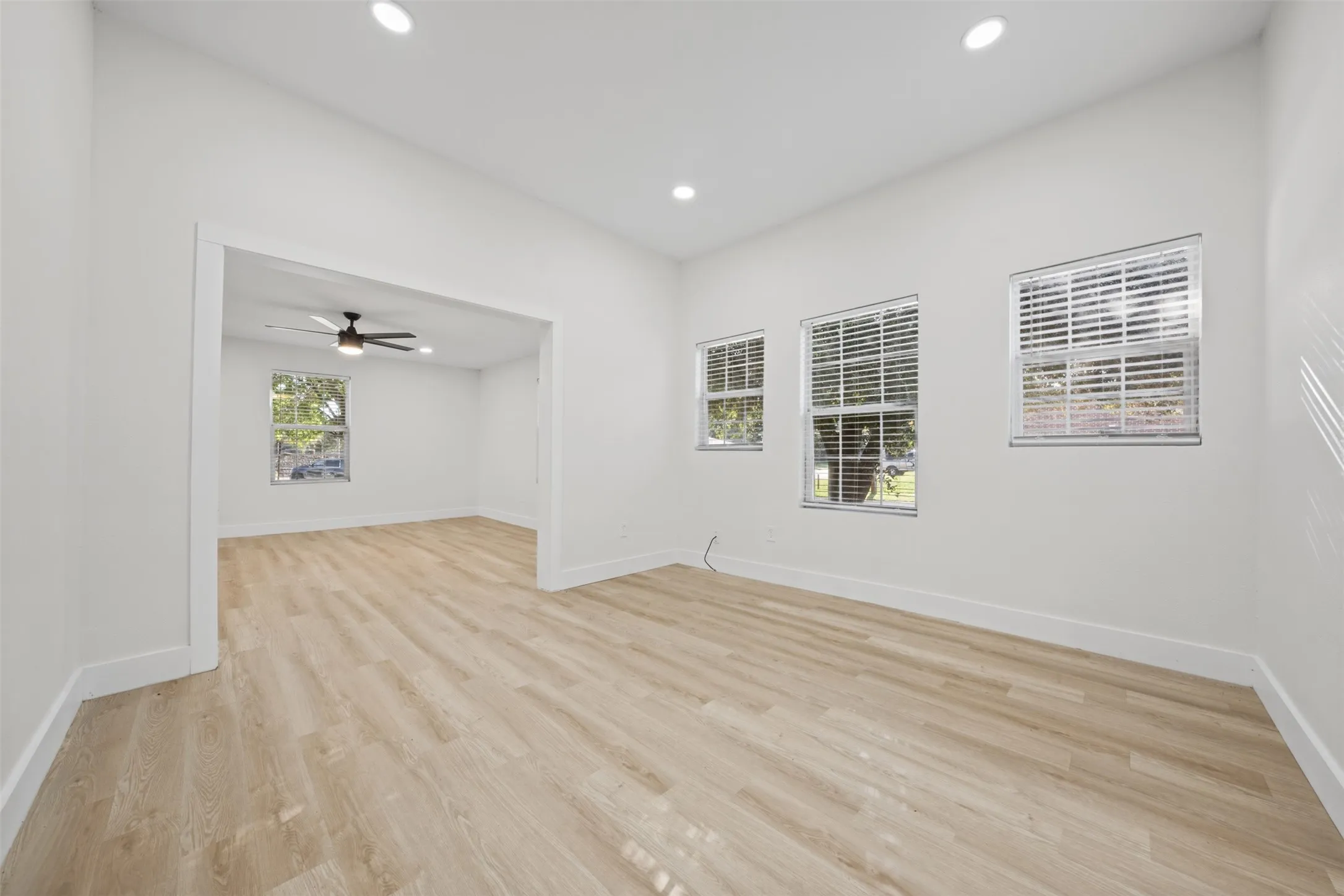 Neutral-toned wood-finish flooring, recessed lighting, and multiple windows with installed blinds
