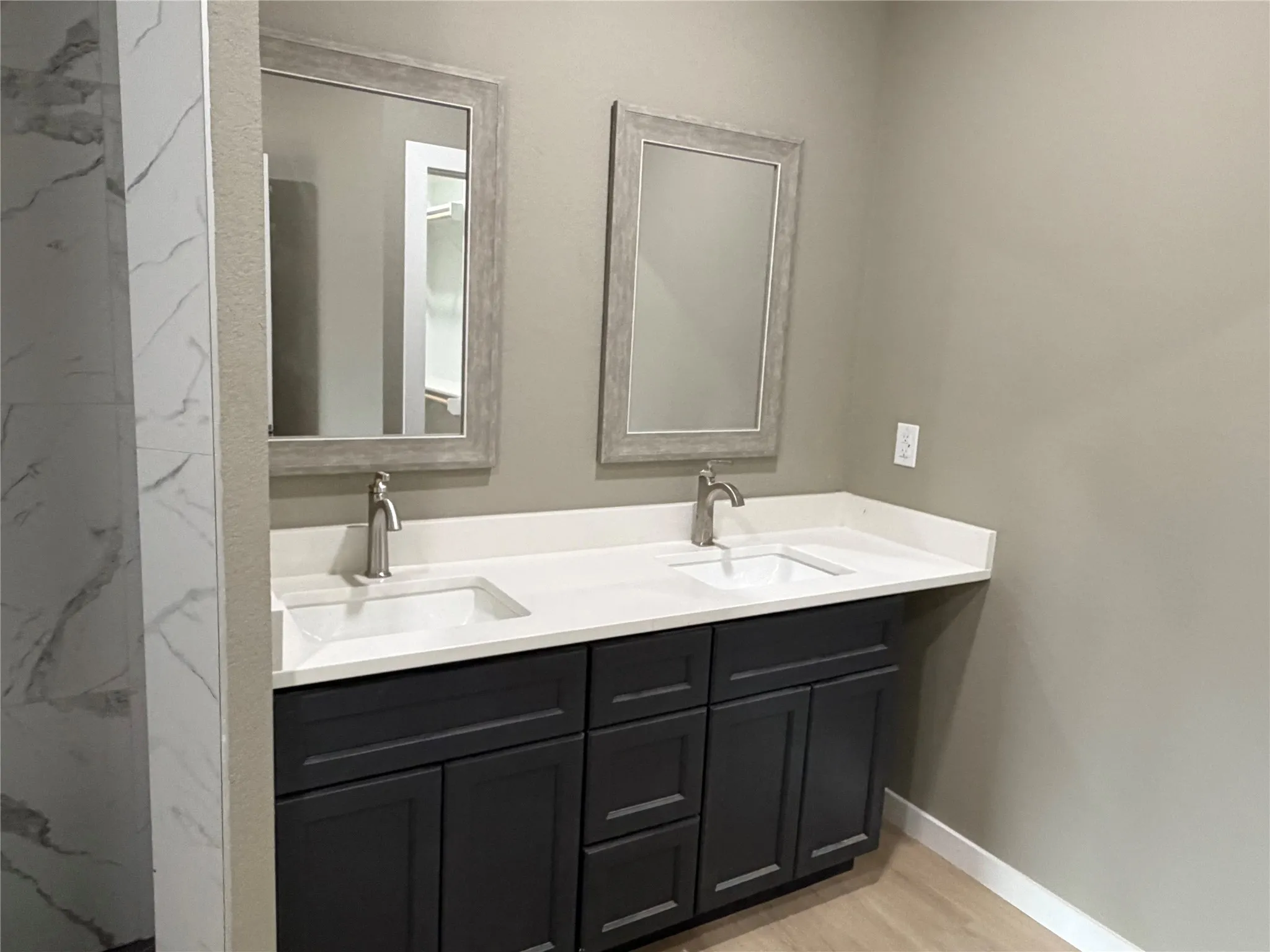Double vanity featuring dark cabinetry, dual undermount sinks, solid surface countertops, and framed mirrors