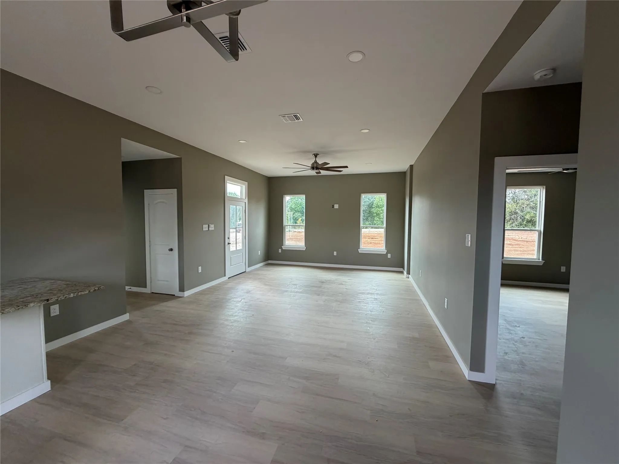 Open-concept interior featuring wood-finish flooring, recessed lighting, a stone-surface breakfast bar, and a ceiling fan