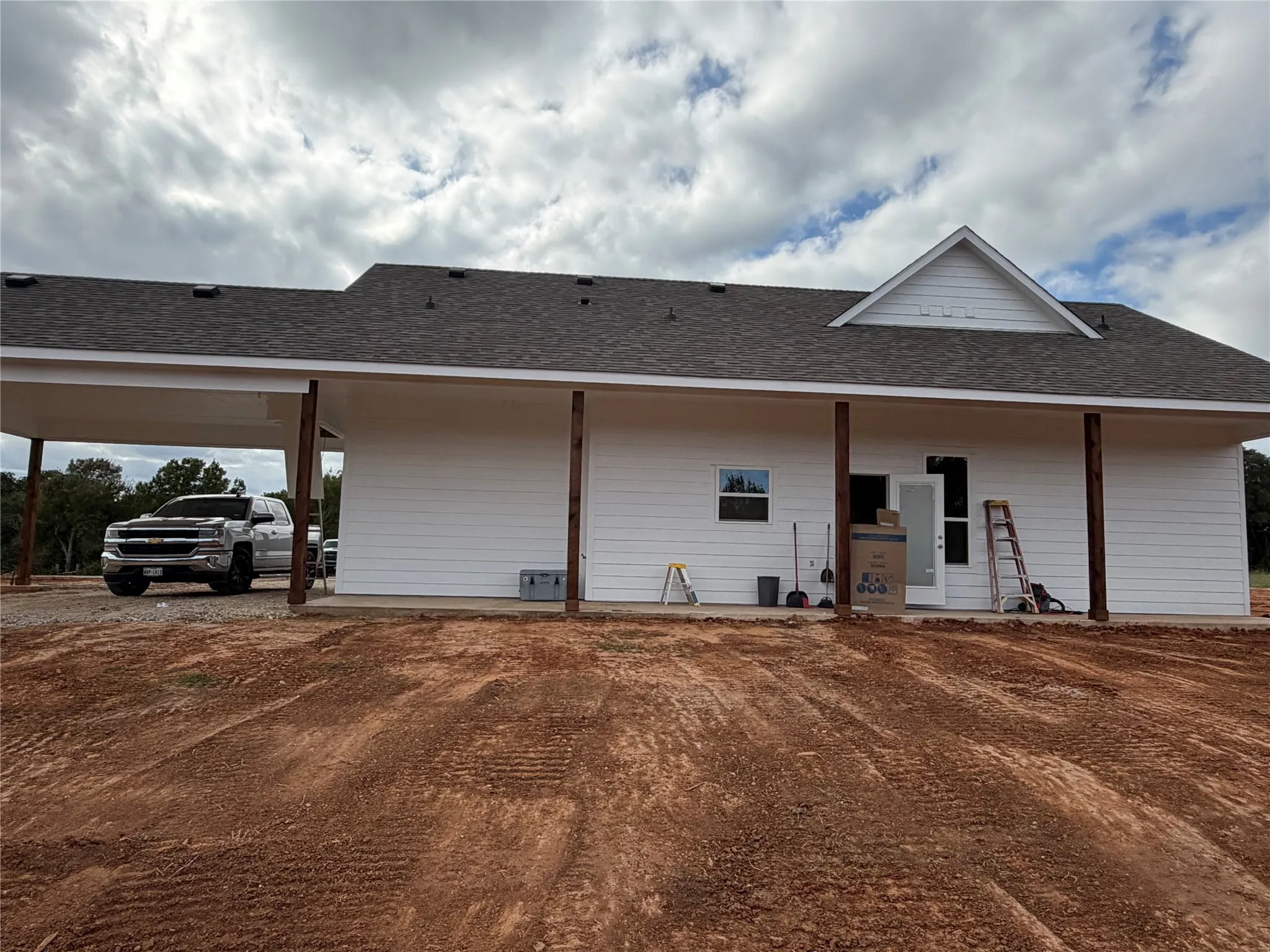 Single-story exterior featuring white horizontal siding, a gabled roofline, and an expansive covered porch supported by wood-finish pillars