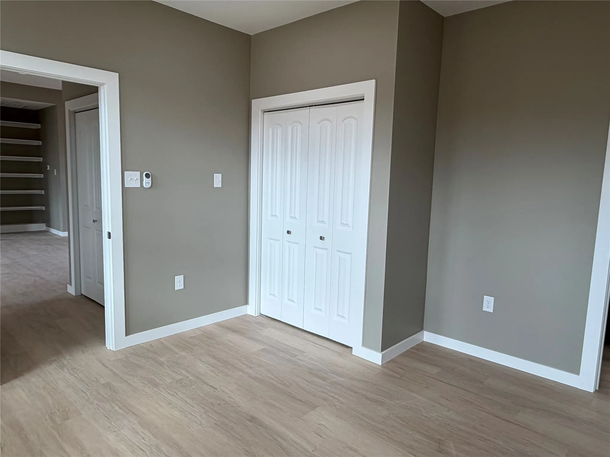 2nd Bedroom Neutral-toned walls, wood-finish flooring, and white double-door closet with paneled detailing