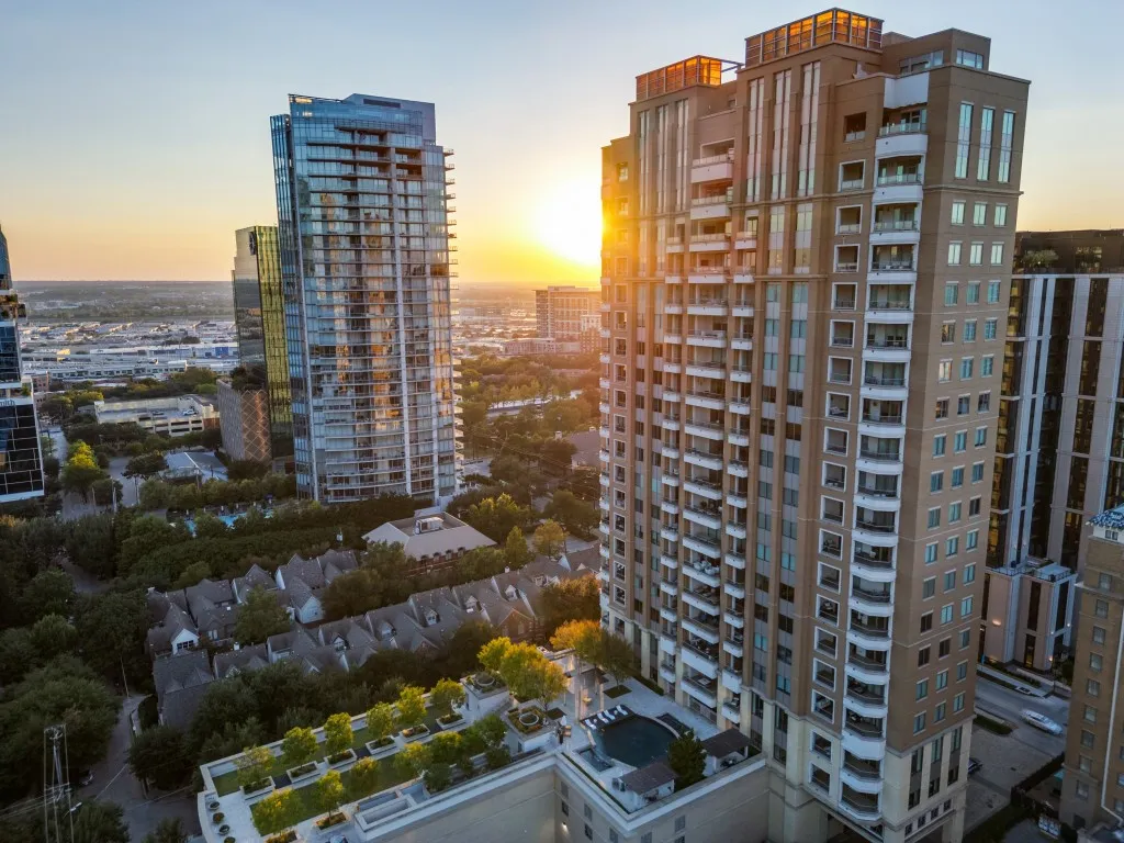 Urban high-rise building featuring multiple balconies and rooftop amenities including a pool area and landscaped green space