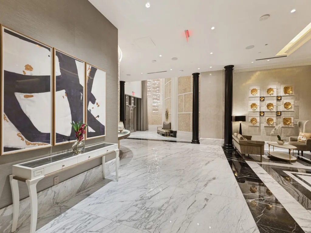 Polished marble flooring throughout, accent wall with textured finish, recessed lighting, and decorative columns