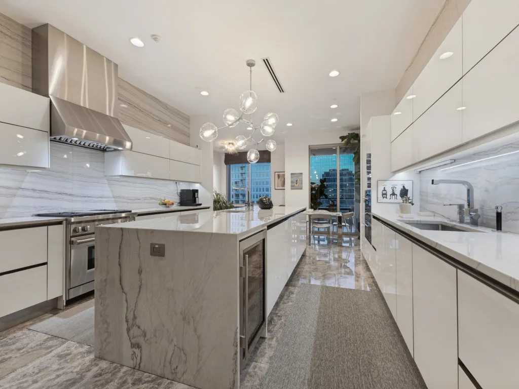Gourmet kitchen featuring a waterfall island, integrated wine refrigerator, stainless steel appliances, and sleek flat-panel cabinetry