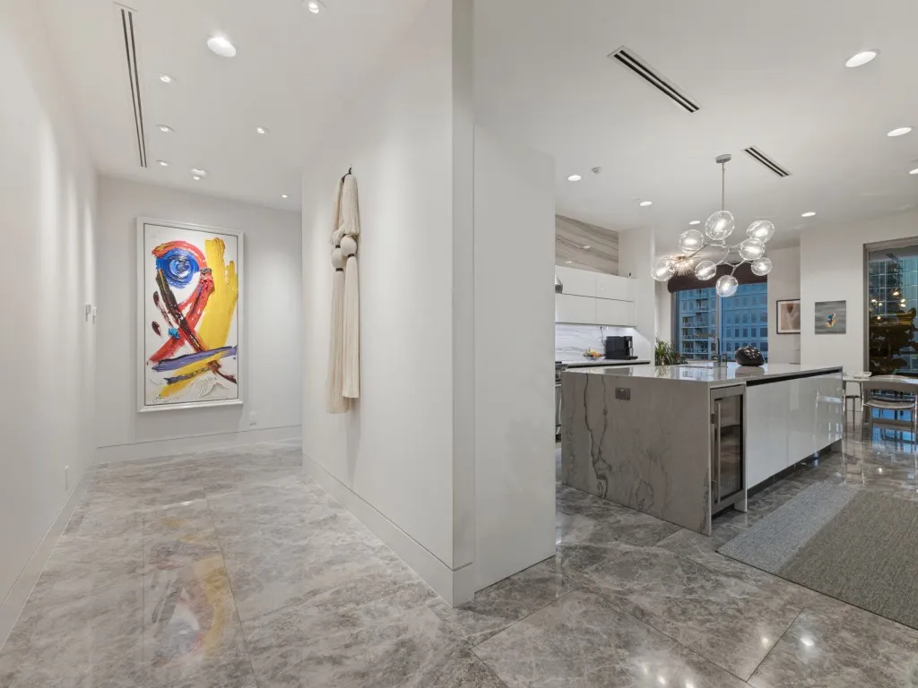 Recessed lighting throughout, gray veined tile flooring, large kitchen island with integrated beverage cooler, contemporary chandelier, and high ceilings