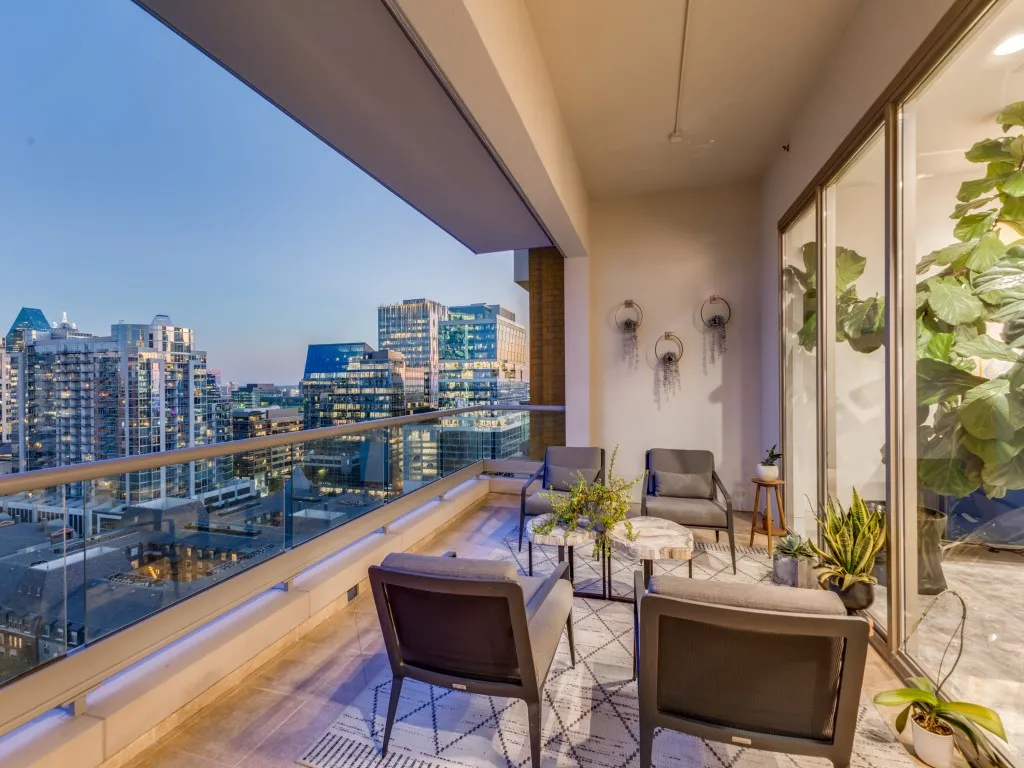 Expansive outdoor terrace featuring a glass railing, city skyline backdrop, and large format tile flooring