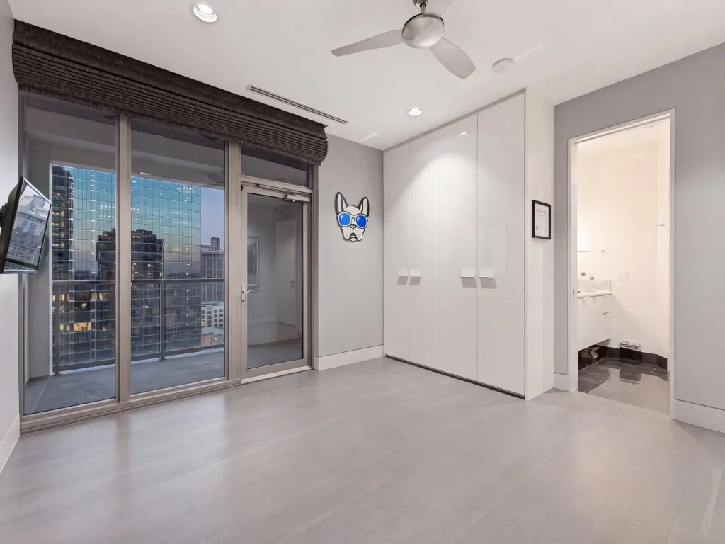 Floor-to-ceiling glass wall with metal-frame balcony door, built-in floor-to-ceiling high-gloss cabinetry, recessed ceiling lighting, ceiling fan, and wood-finish flooring