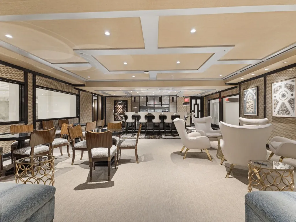 Recessed lighting, layered ceiling design, built-in bar, patterned wall panels, and interior windows
