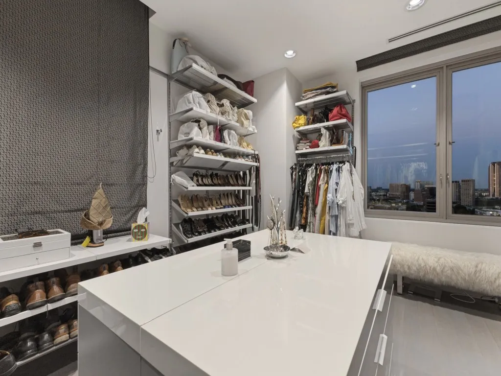 Built-in shelving units, central island with storage, window with urban backdrop, recessed lighting, and roller shade