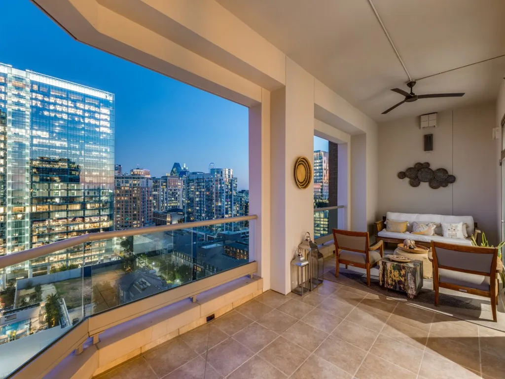 Expansive balcony featuring a glass railing, tiled flooring, a built-in ceiling fan, and recessed lighting