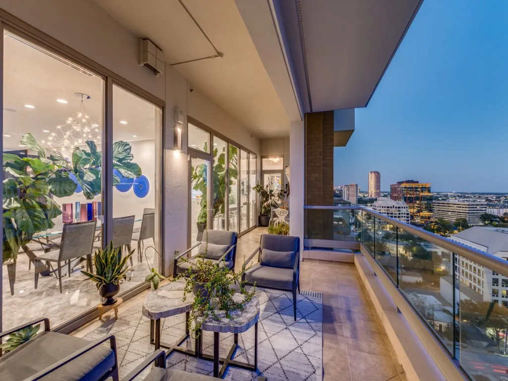 Expansive outdoor balcony featuring a tiled surface and a glass railing system