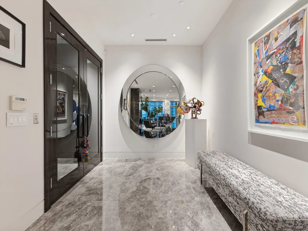 Entryway featuring large format grey-veined tile flooring, a circular mirror, and recessed lighting